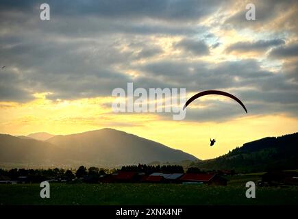 Il parapendio atterra al tramonto presso il sito di sbarco di Oberammergau, Baviera, Germania Foto Stock