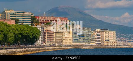 Vista dell'architettura color pastello, dei ristoranti e dei caffè sul lungomare di via Partenope e del Vesuvio, Napoli, Campania, Italia, Europa Foto Stock