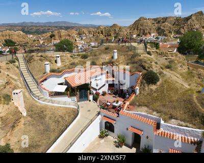 Una casa bianca con tetto in terracotta su una collina circondata dalla natura e alcune persone si godono il paesaggio, la vista aerea, le abitazioni nelle grotte, la grotta Foto Stock