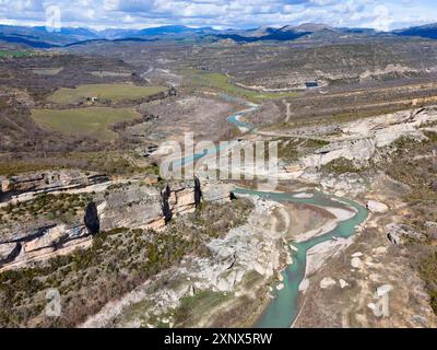 Vista aerea di uno splendido paesaggio montano con ripide pareti rocciose e un fiume che si snoda attraverso la valle, sotto un cielo nuvoloso, vista aerea Foto Stock