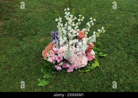 Finti fiori di plastica collocati sul campo verde sono solo per la decorazione temporanea della sede dell'evento Foto Stock