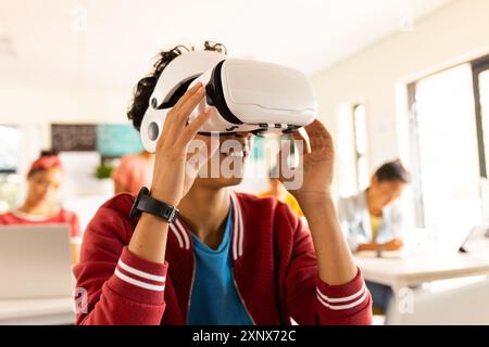 Al liceo, adolescente che usa il visore VR in classe, esplorando la realtà virtuale Foto Stock