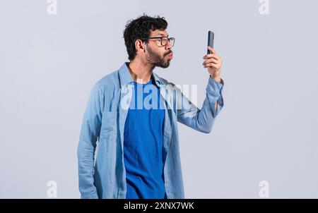 Funny Man che fa baci al cellulare isolato. un giovane che si fa selfie e baci sul cellulare isolato Foto Stock