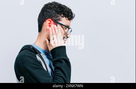 Concetto di persona con otite e tinnito, persona con dolore all'orecchio, su sfondo isolato, uomo sofferente massaggiando l'orecchio isolato Foto Stock