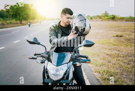 Giovane motociclista che indossa il casco di sicurezza all'aperto. Motociclista maschile che indossa il casco. Concetto di sicurezza per motociclisti Foto Stock