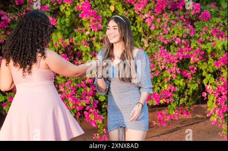 Due amiche che sbattono e stringono la mano all'aperto. Due ragazze sorridenti che stringono la mano per strada Foto Stock