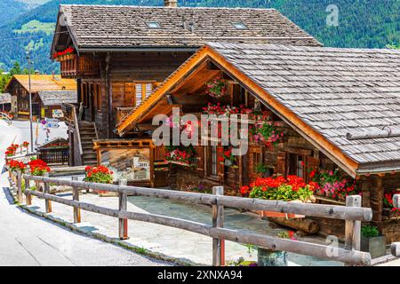 Vecchie case in legno con fioriere davanti alle finestre e sulla recinzione in legno, centro storico del paese, Grimentz, Val d'Anniviers, Alpi Vallese Foto Stock