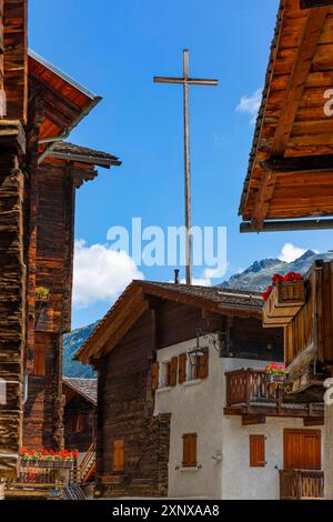 Grande croce di legno sopra vecchie case nel centro storico del paese, Grimentz, Val d'Anniviers, Alpi Vallese, Canton Vallese, Svizzera Foto Stock