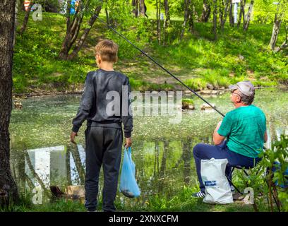 Mosca, Russia - 12 maggio 2023: Nonno e nipote pesca sulla riva di uno stagno Foto Stock