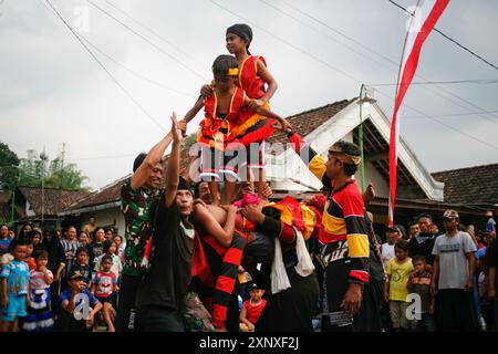 Due ragazzi in piedi sul corpo di una ballerina di barong cadono in trance nel villaggio di Sukomoro, Puncu Kediri, Giava orientale, Indonesia. Foto Stock