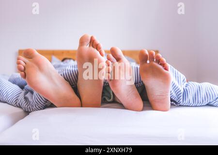 Primo piano una coppia scoperto piedi dormendo in letto, mattina Foto Stock