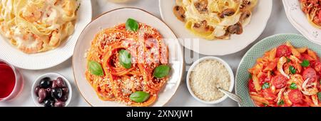 Panorama gastronomico italiano. Vari tipi di pasta, olive e parmigiano, sparati dall'alto su uno sfondo di marmo bianco Foto Stock