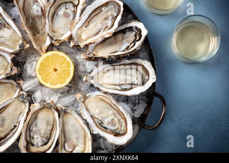 Ostriche con vino, scattate dall'alto su uno sfondo blu con spazio di copia Foto Stock