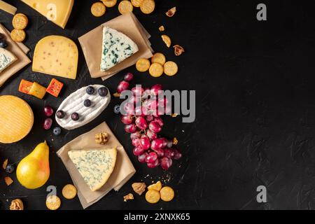 Varietà di formaggi, con frutta e spuntini, shot dall'alto su uno sfondo nero con un posto per il testo Foto Stock