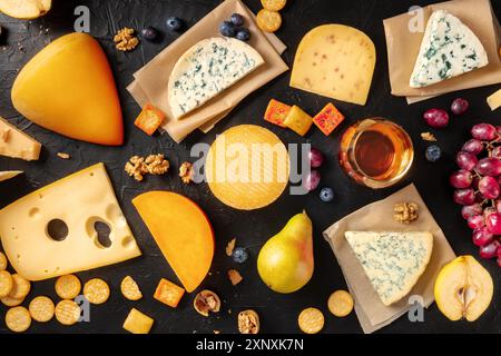 Formaggio, vino e frutta. Una varietà di formaggi, sparati dall'alto su uno sfondo nero Foto Stock