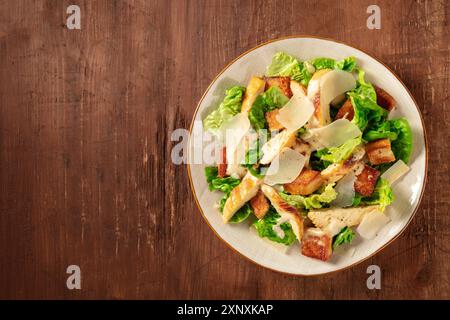 Caesar Salad con pollo, top shot con un posto per il testo su uno sfondo rustico scuro in legno Foto Stock