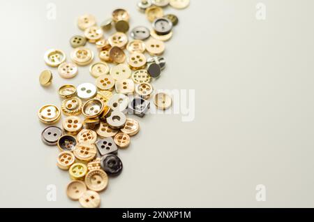 Una pila di bottoni di varie forme e dimensioni. I pulsanti sono sparsi nell'immagine, con alcuni che si sovrappongono l'uno all'altro. Concetto di abbondanza e. Foto Stock