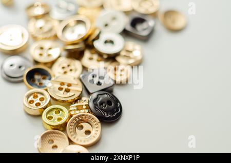 Una pila di bottoni di varie forme e dimensioni. I pulsanti sono sparsi nell'immagine, con alcuni che si sovrappongono l'uno all'altro. Concetto di abbondanza e. Foto Stock