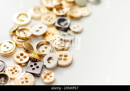 Una pila di bottoni di varie forme e dimensioni. I pulsanti sono sparsi nell'immagine, con alcuni che si sovrappongono l'uno all'altro. Concetto di abbondanza e. Foto Stock