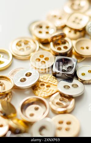 Una pila di bottoni di varie forme e dimensioni. I pulsanti sono sparsi nell'immagine, con alcuni che si sovrappongono l'uno all'altro. Concetto di abbondanza e. Foto Stock