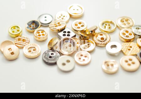 Una pila di bottoni di varie forme e dimensioni. I pulsanti sono sparsi nell'immagine, con alcuni che si sovrappongono l'uno all'altro. Concetto di abbondanza e. Foto Stock