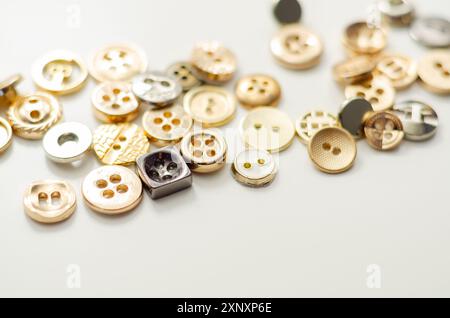 Una pila di bottoni di varie forme e dimensioni. I pulsanti sono sparsi nell'immagine, con alcuni che si sovrappongono l'uno all'altro. Concetto di abbondanza e. Foto Stock
