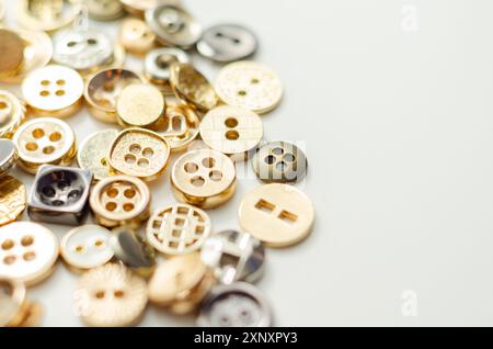 Una pila di bottoni di varie forme e dimensioni. I pulsanti sono sparsi nell'immagine, con alcuni che si sovrappongono l'uno all'altro. Concetto di abbondanza e. Foto Stock