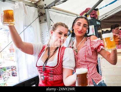 Herne, NRW, Germania. 2 agosto 2024. Due cameriere servono con un sorriso. Cranger Kirmes, la seconda fiera più grande della Germania (dopo l'Oktoberfest di Monaco), si apre con la tradizionale spillatura del barile, effettuata dal sindaco Frank Dudda, dal vice PM dell'NRW Mona Neubaur e da altri, oltre all'intrattenimento della cantante tedesca Vanessa mai. La vivace fiera ha una lunga tradizione che risale al XV secolo, dove un mercato di cavalli e successivamente intrattenitori medievali, legnavano la folla. Cranger Kirmes attrae circa 4 milioni di visitatori ogni anno in un sito dedicato lungo il canale Reno-Herne. Foto Stock