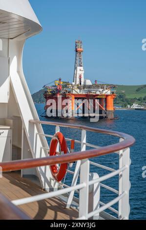 Piattaforma petrolifera Transocean leader con nave da crociera di fronte a Invergordon in cielo limpido, colpo verticale Foto Stock