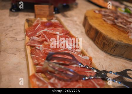 Presentazione di un lussuoso prosciutto stagionato su un piatto di legno in un hotel di fascia alta Foto Stock