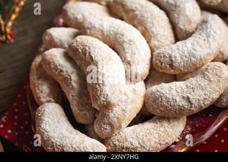 Biscotti di Natale fatti in casa chiamati Kipferl o mezzaluna di vaniglia ricoperte di zucchero su un piatto rosso, primo piano Foto Stock