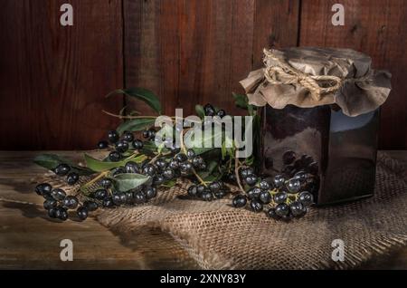 Bacche e un vasetto di marmellata su uno sfondo di legno scuro in stile rustico Foto Stock