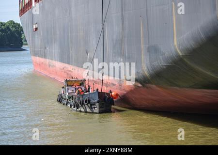 La nave cisterna o la chiatta bunker presso lo scafo di un grande cargo di container prende in consegna i residui oleosi e le acque reflue sanitarie nel porto di Amburgo Foto Stock