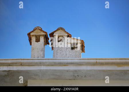 Camini in intonaco chiaro con tetti in tegole su un edificio in Grecia, come piccole case, cielo blu con spazio copia, selezionato fuoco Foto Stock