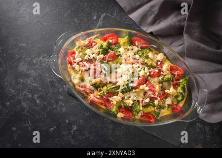 Casseruola di broccoli, pomodori, cipolle, feta e formaggio, piatto di verdure sano su sfondo grigio scuro di ardesia, vista dall'alto, copia Foto Stock