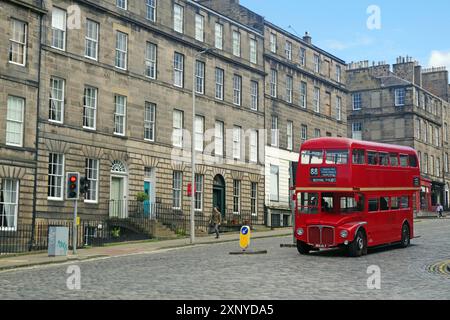 L'autobus rosso a due piani attraversa una strada acciottolata in un paesaggio urbano storico, Old Town, Edinburgh, Scotland, Regno Unito Foto Stock