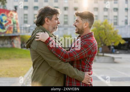 Felice coppia gay sposata che abbraccia mentre si guardano all'aperto Foto Stock
