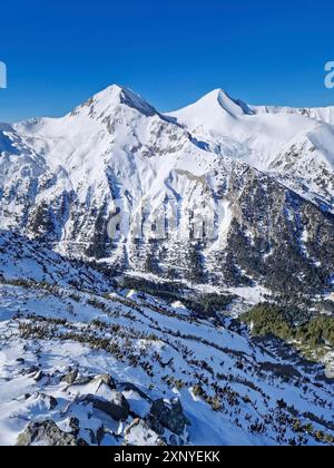 Vista aerea sulle montagne Pirin con cime rocciose ricoperte di neve. Vista invernale della stazione sciistica di Bansko in Bulgaria Foto Stock
