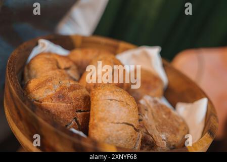Rotoli di pane artigianali in ciotola di legno su panno bianco in un ambiente raffinato Foto Stock