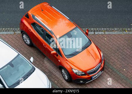 OSTRAVA, REPUBBLICA CECA - 12 LUGLIO 2024: Orange Opel Mokka Un parcheggio incrociato sulla strada, vista dall'alto Foto Stock