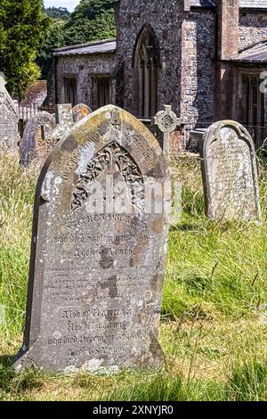 Aldbourne / Inghilterra - 25 giugno 2024: Antiche pietre tombali in pietra intemperie adornano un cimitero medievale della chiesa il 25 giugno 2024 ad Aldbourne, Inghilterra. Foto Stock