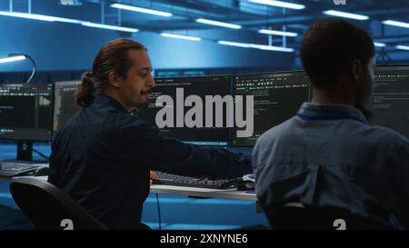 Manager supervisiona la sala server e beve caffè durante l'esecuzione del codice sul PC, risolvendo i problemi hardware. Programmazione dell'amministratore di sistema nella server farm sul computer e utilizzo di bevande calde Foto Stock