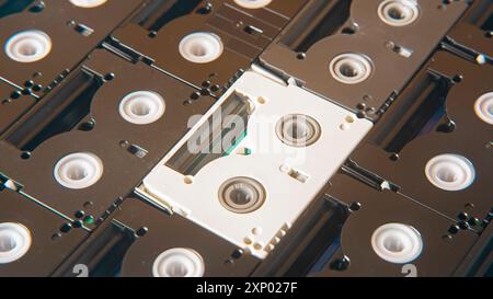 Sfondo di vecchie cassette mini DV nere che circondano una cassetta bianca Foto Stock