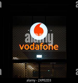 Pubblicità illuminata del fornitore di telefonia mobile Vodafone nel centro di Berlino in serata Foto Stock