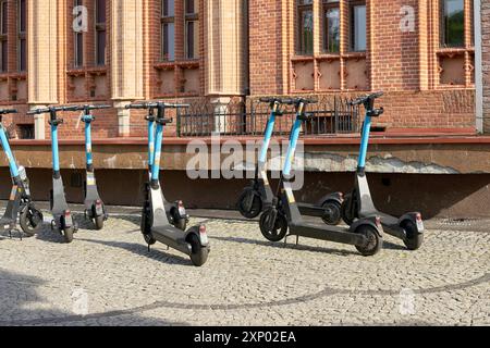 Gli e-scooter OKAI parcheggiati sono disponibili per il noleggio di fronte al municipio di Kolberg in Polonia Foto Stock