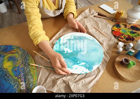 Artista femminile che crea pittura d'arte fluida a tavola in laboratorio Foto Stock