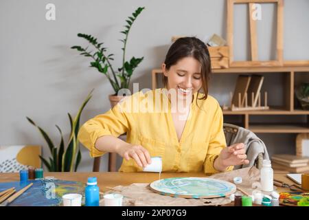 Artista femminile che crea pittura d'arte fluida a tavola in laboratorio Foto Stock