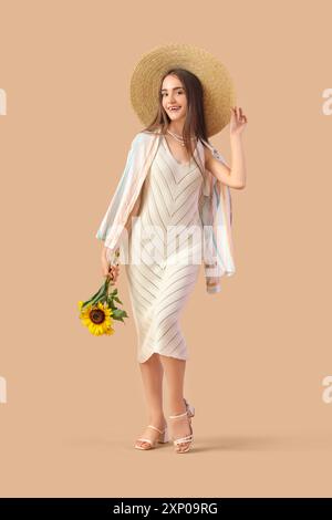 Bella giovane donna con bouquet di girasoli su sfondo beige Foto Stock