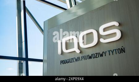 Una foto del logo IQOS sul lato di uno stand all'interno del terminal dell'aeroporto Chopin di Varsavia. Lo slogan si legge come Foto Stock