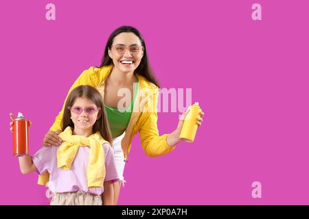 La bambina e sua madre con bombolette spray su sfondo viola Foto Stock